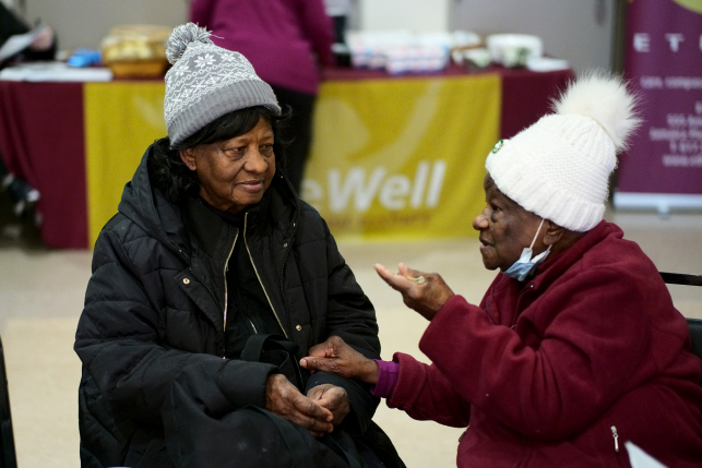 Two senior citizens in hats talk inside