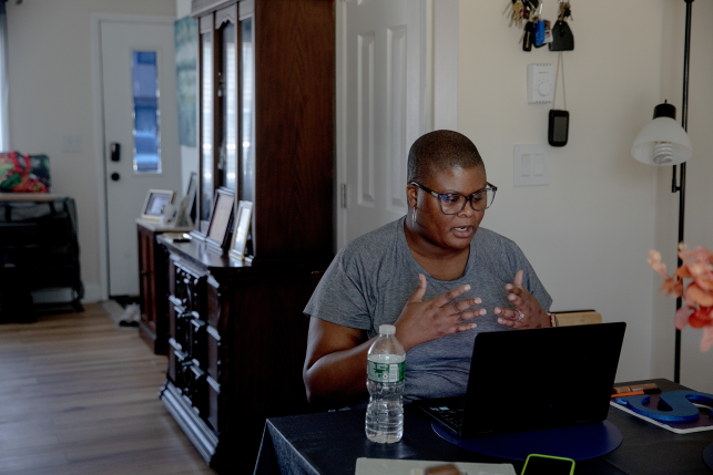 Woman talks to computer at desk in home