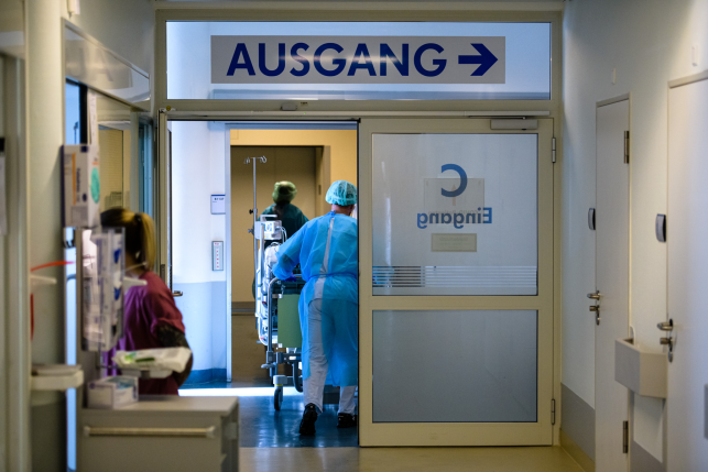 Doctor and nurses tend to a patient in Germany with a sign that reads “Ausgang” and an arrow above the door