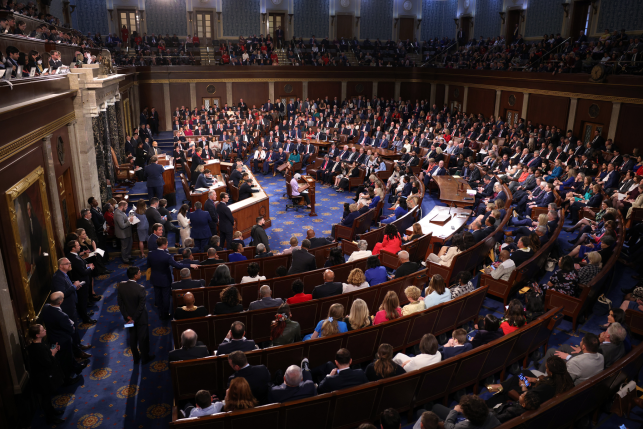 Members of the U.S. House of Representatives seated and standing in the House Chamber of the U.S. Capitol Building in Washington, D.C.