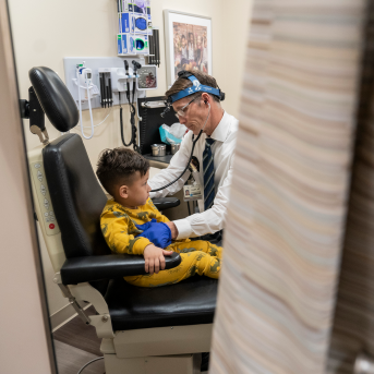 Child in doctors chair with doctor standing over him
