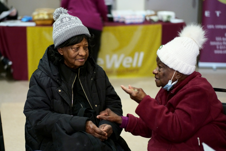 Two senior citizens in hats talk inside