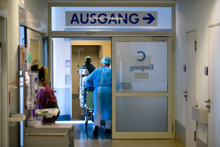 Doctor and nurses tend to a patient in Germany with a sign that reads “Ausgang” and an arrow above the door