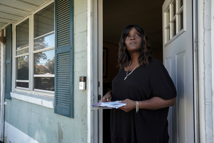 Woman holds bills while looking out the door