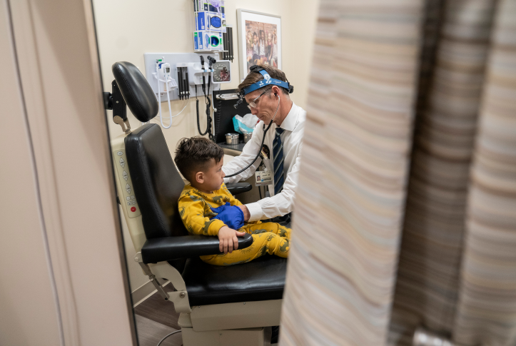Child in doctors chair with doctor standing over him