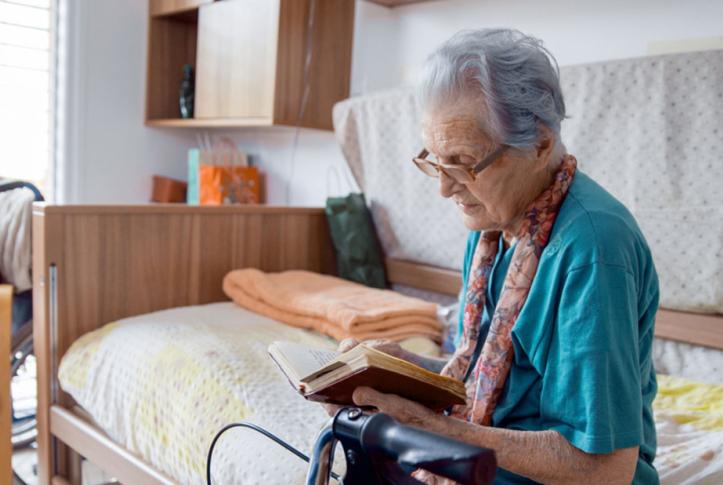 Medicare senior who is seriously ill reading on bed