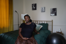 Pregnant woman sits on bed next to birthing ball