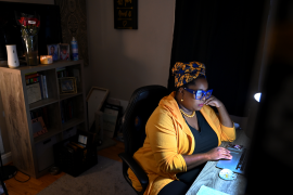 Woman sits in darkness at her home office computer